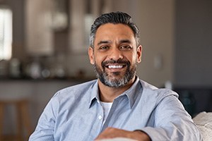 Man in blue shirt smiling on couch