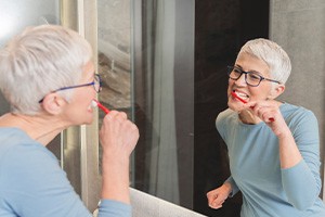 Woman smiling while brushing teeth in bathroom