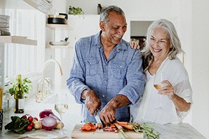 Senior couple smiling while preparing meal at home