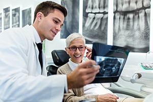 Smiling patient looking at X-ray with dentist