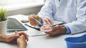 A dentist pointing to a model of a mouth