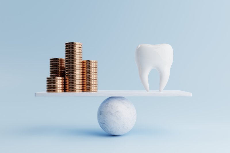 A 3D tooth and golden coins on a balancing scale against a blue background